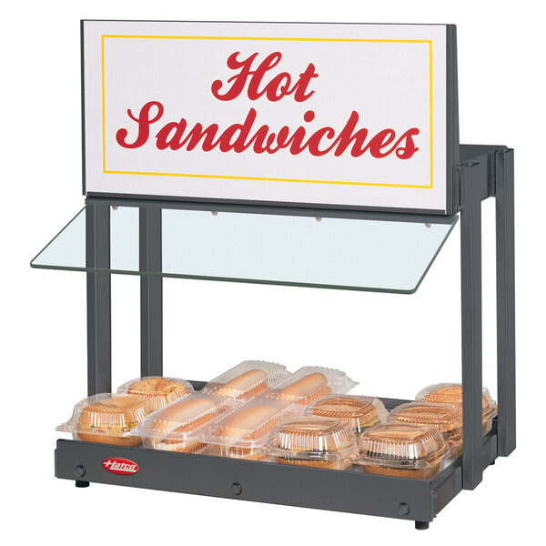 A Hatco mini-merchandising warmer with hot sandwiches and a sign.