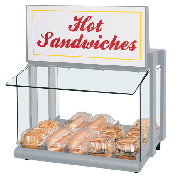 A Hatco countertop hot food display warmer with hot dogs and buns in a plastic container.