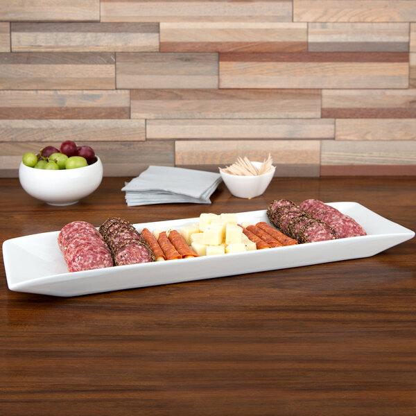 A Cal-Mil long rectangular porcelain platter with meat, cheese, and grapes on it.