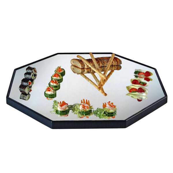 A Cal-Mil octagonal mirror tray with a raised black rim holding a plate of food on a white table.