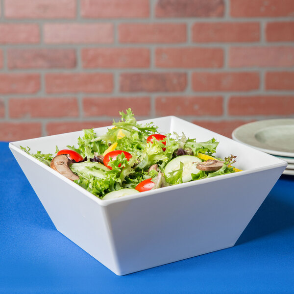 A white Cal-Mil square melamine bowl filled with salad on a table.