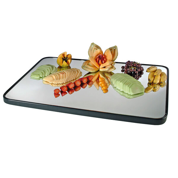A Cal-Mil mirror tray with fruit on it, including flowers carved from fruit.