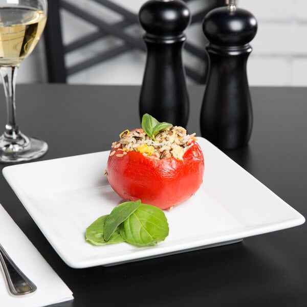 A Tuxton TuxTrendz bright white square china plate with a stuffed tomato with rice and corn on it.