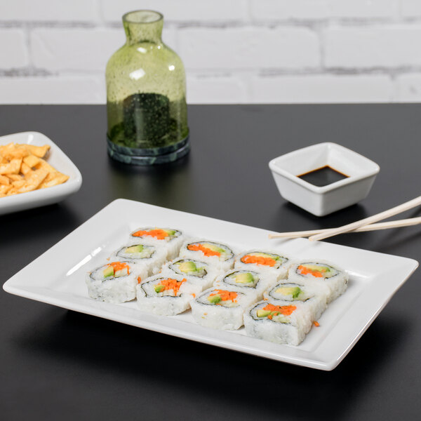 A rectangular white Tuxton china plate with sushi on it.