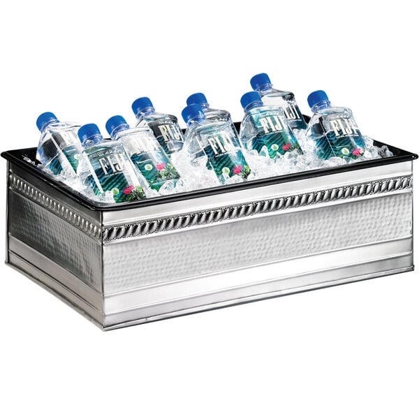 A Cal-Mil stainless steel container holding several bottles of water on a table.