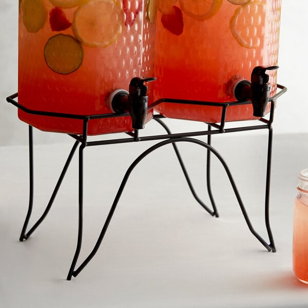 A metal stand with two Acopa glass beverage dispensers filled with fruit and lemonade.