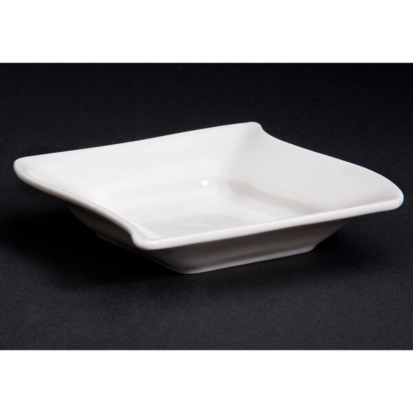 A CAC Soho ivory square stoneware bowl with a curved edge.