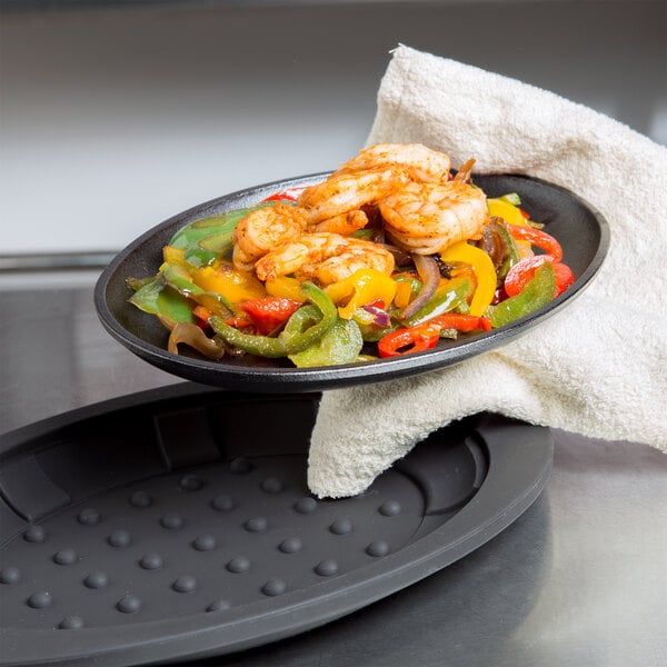 A hand holding a plate of food cooked in a Lodge oval cast iron fajita skillet.