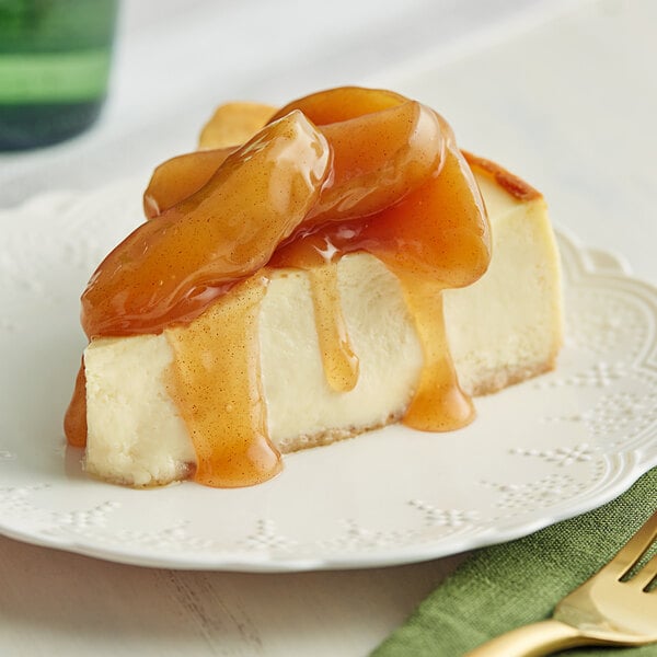 A slice of cheesecake with caramel sauce on top on a plate with a fork and knife.