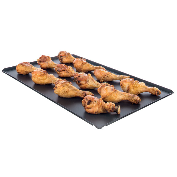 A Rational 12" x 20" roasting tray of fried chicken legs.