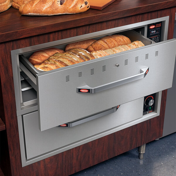 A Hatco built-in drawer warmer with bread in one drawer and a pan in the other.