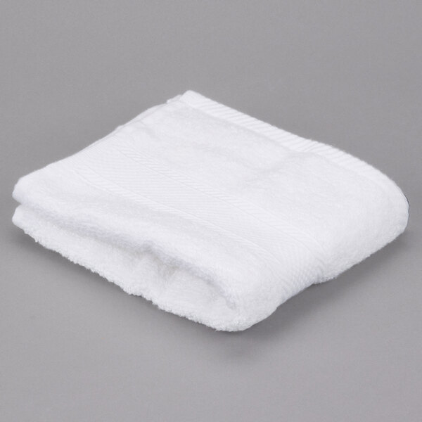 A folded white Oxford Miasma hand towel on a gray surface.