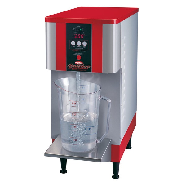 A red and silver Hatco hot water dispenser on a counter with a pitcher of water.