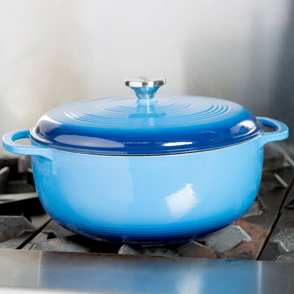 A Caribbean blue Lodge enameled cast iron dutch oven on a stove.