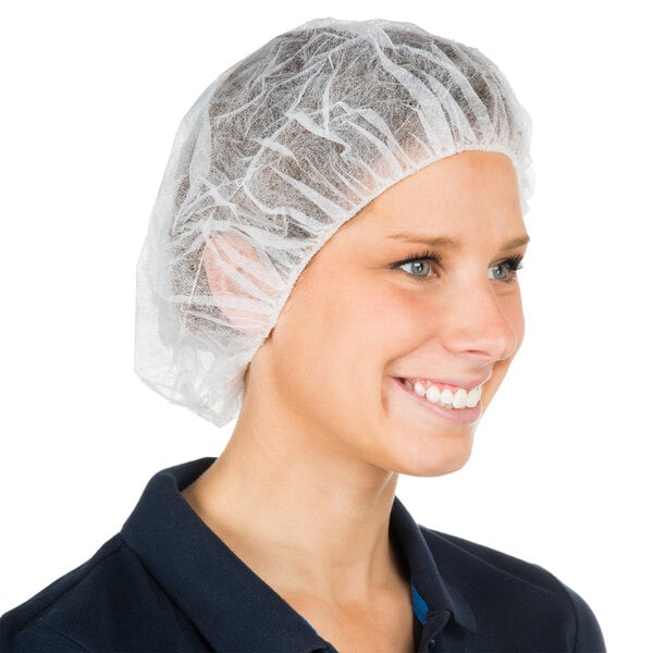 A woman wearing a white Chef Revival hair net smiling.