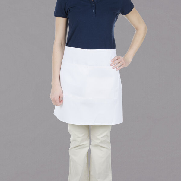 A woman wearing a Chef Revival white bistro apron with 2 pockets.