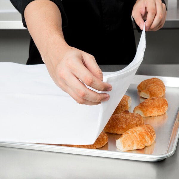 A person holding a Choice white flour sack towel over a tray of pastries.