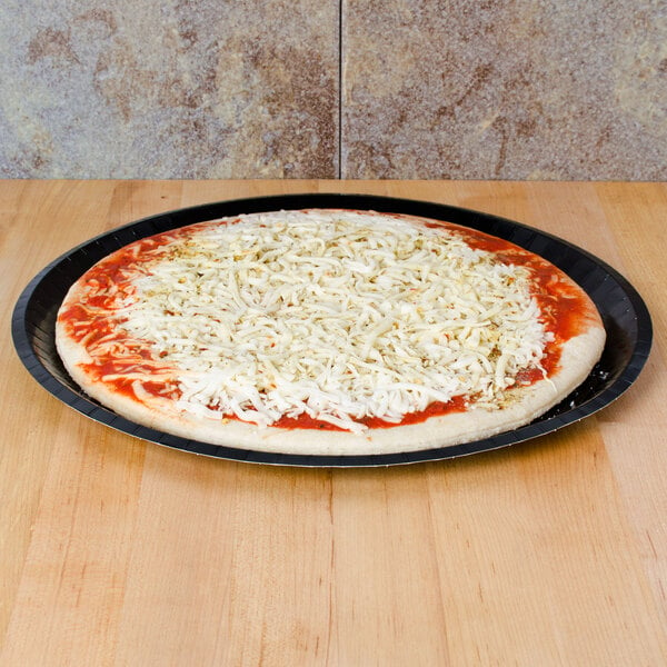 A Solut black coated paperboard pizza tray with a pizza with cheese on it.