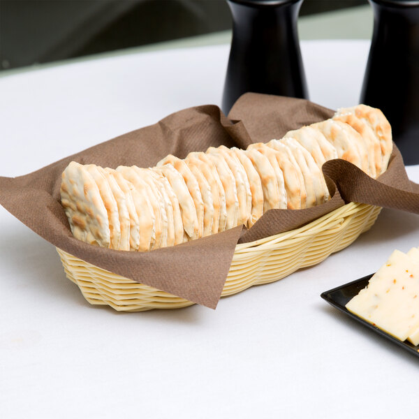A Thunder Group rattan cracker basket on a table with crackers.