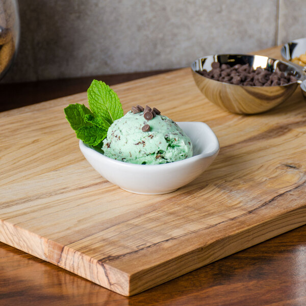A white ceramic American Metalcraft sauce cup filled with mint chocolate chip ice cream topped with mint leaves and chocolate chips.