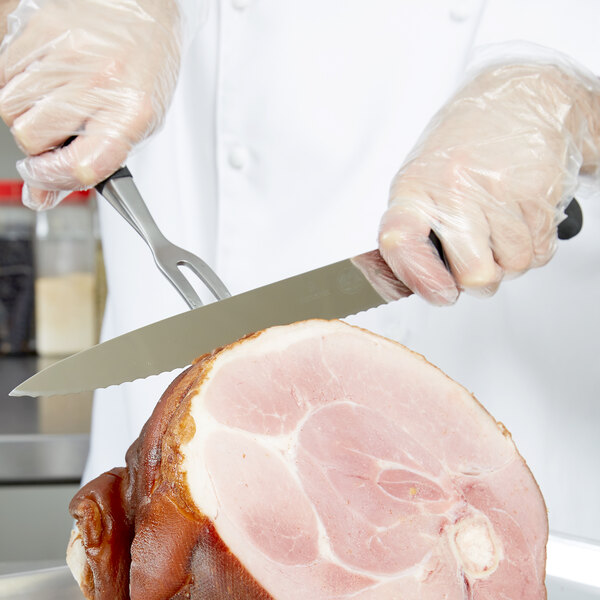 A person using a Victorinox serrated carving knife to slice meat.
