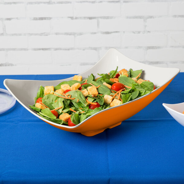 A sunset flare melamine bowl filled with salad on a table.