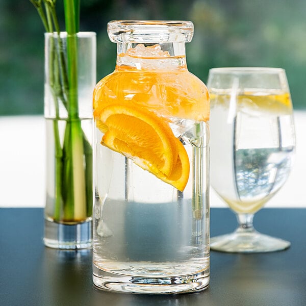 A Libbey Helio water bottle filled with water and a slice of orange on a table.