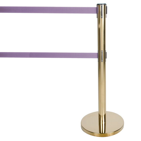 A gold Aarco crowd control stanchion with purple retractable belts on the pole.