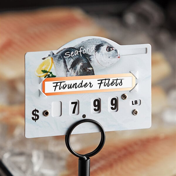 A close up of a fish on a plate with a Choice Deli Tag for seafood.