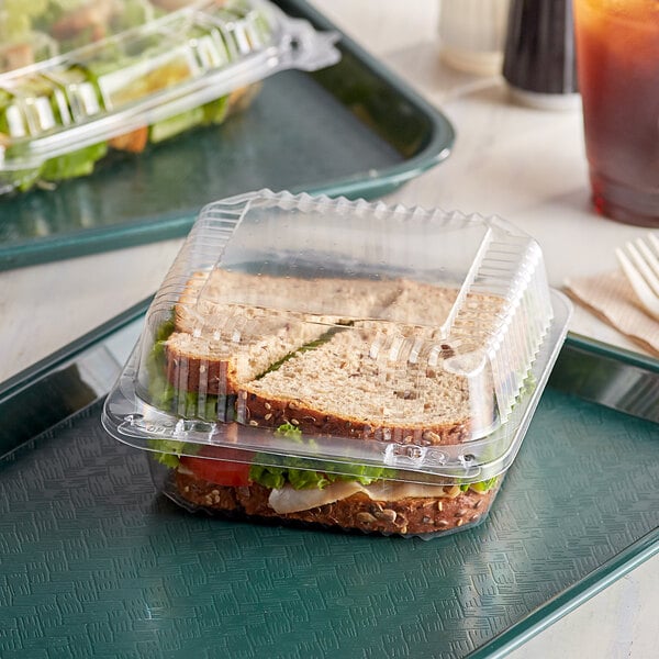 A sandwich in a Dart clear hinged plastic container on a table.