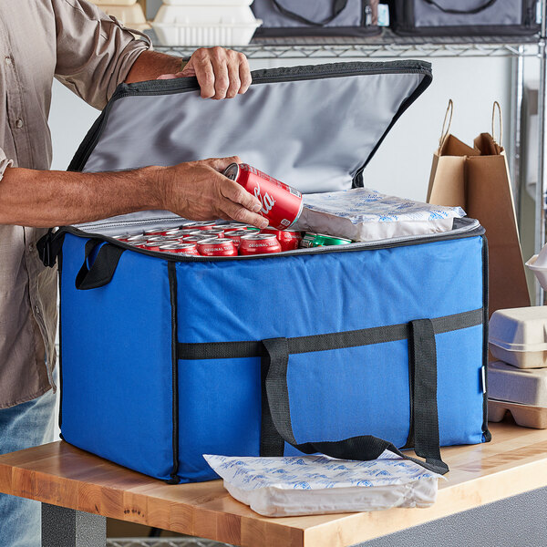 A man putting a blue can into a Choice large blue insulated cooler bag.