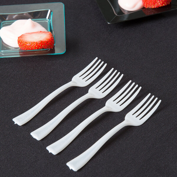 A row of Fineline white plastic tasting forks on a table.