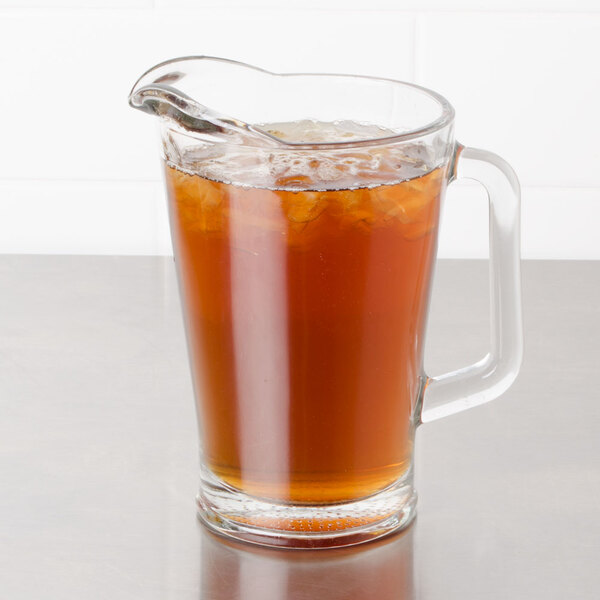 A glass pitcher and cup of Bromley Black Iced Tea on a table.