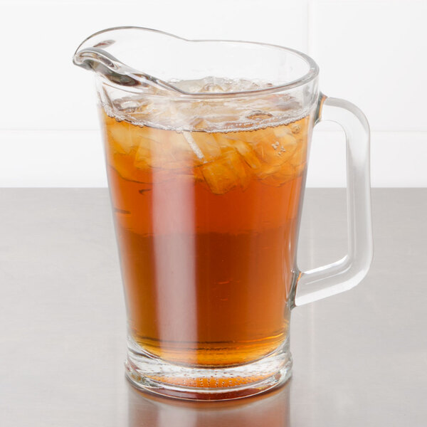 A glass pitcher of iced tea with a liquid-filled glass and ice.