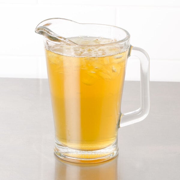 A glass pitcher of Bromley Lemon Ginseng Green Iced Tea with a glass and ice.