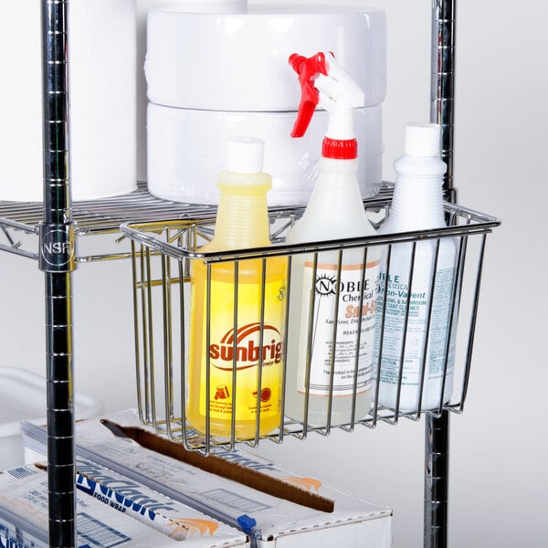 A Regency chrome metal basket holding cleaning supplies including a bottle with a black label.