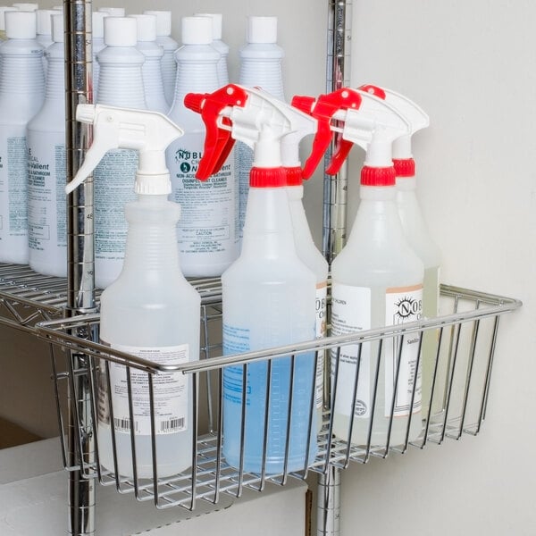 A Regency chrome storage basket on a metal shelf holding white plastic spray bottles.