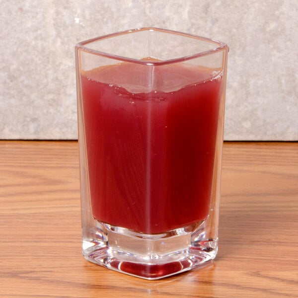 A Thunder Group plastic square dessert shot glass with red liquid in it on a table.