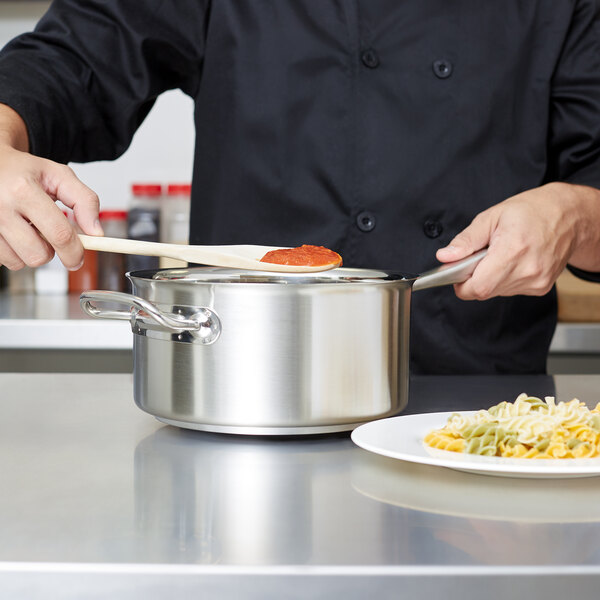 A chef using a Vollrath stainless steel sauce pan on a counter.