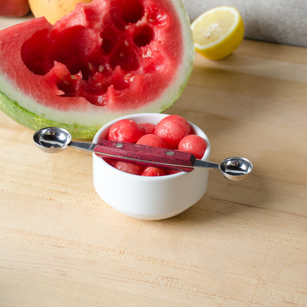 A bowl of watermelon and a cut watermelon with a Thunder Group Double Melon Baller.