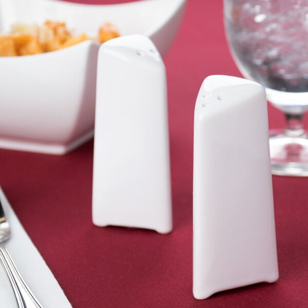 Two white porcelain triangle salt and pepper shakers on a table.