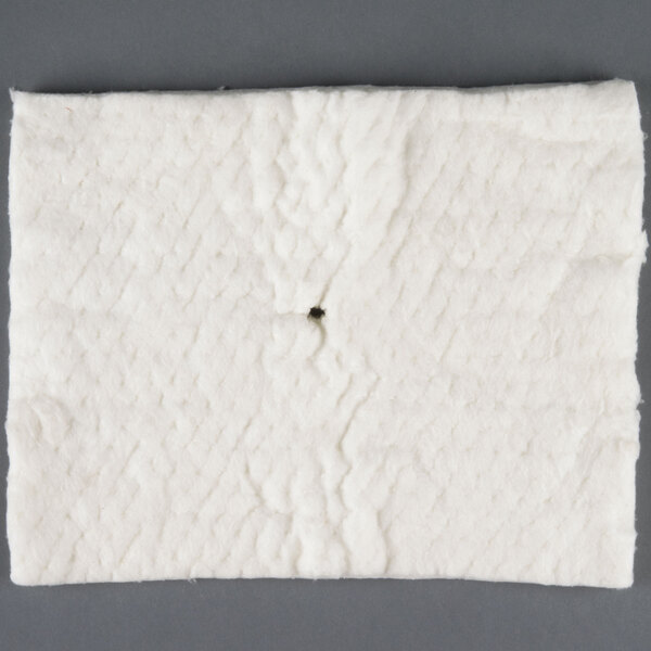 A white square cloth with a black spot on it with a hole in the center.