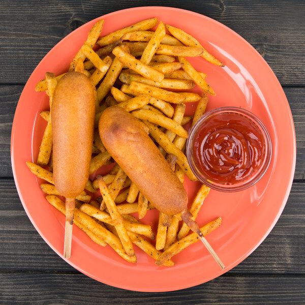 A corn dog and French fries on a Carlisle Sunset Orange melamine plate with ketchup.