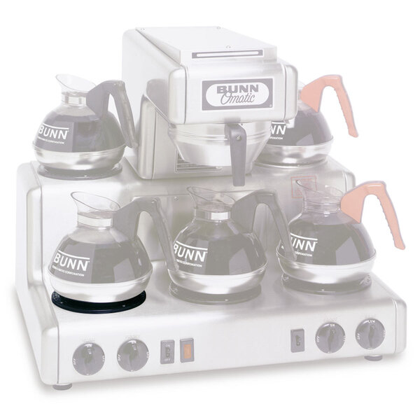 A Bunn black lower dish assembly on a coffee maker with several coffee pots.