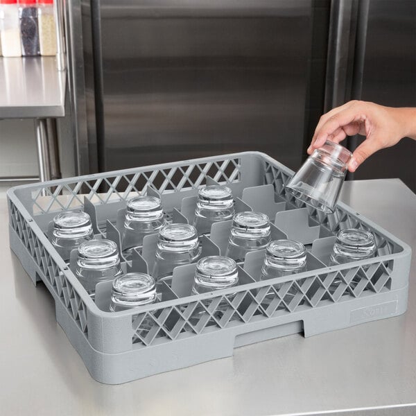 A hand holding a glass over a Noble Products 16-compartment glass rack.