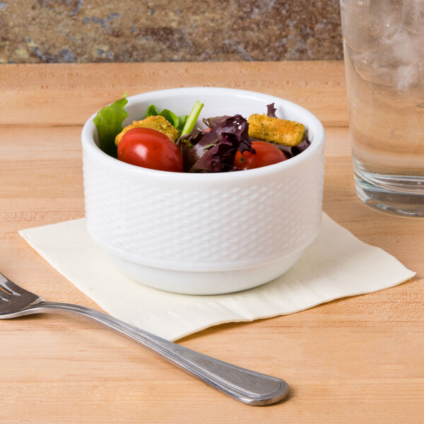 A CAC Boston white porcelain bowl filled with salad on a table with a fork.