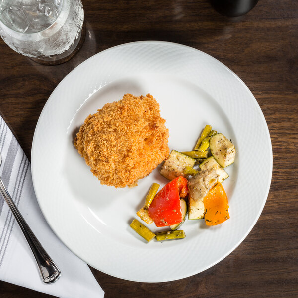 A CAC porcelain plate with a piece of fried chicken and vegetables on a white surface.