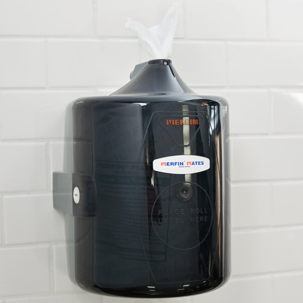 A black plastic wall mount wipes dispenser on a white wall.