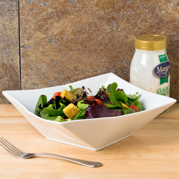 A table set with a CAC Bright White Square Porcelain bowl filled with salad.