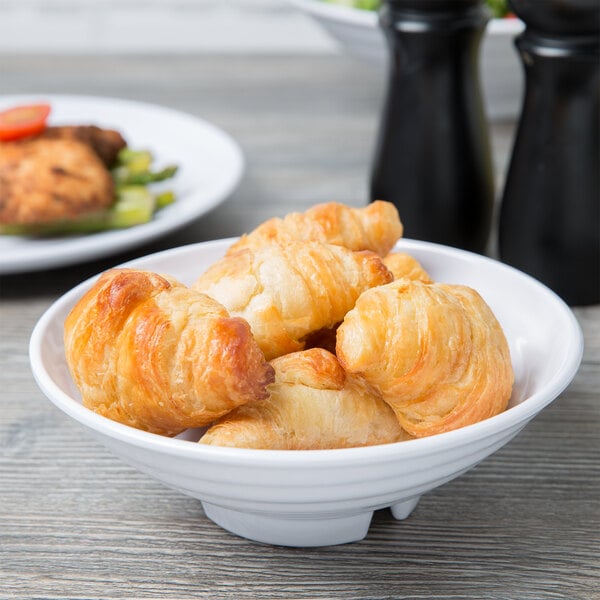 A white Milano melamine bowl filled with croissants on a table.